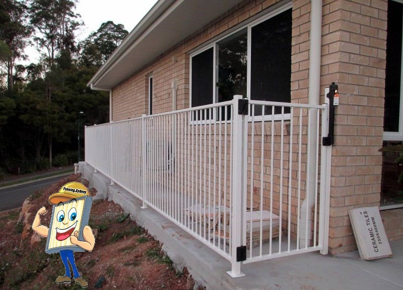 White flat top pool fence and gate beside a brick home