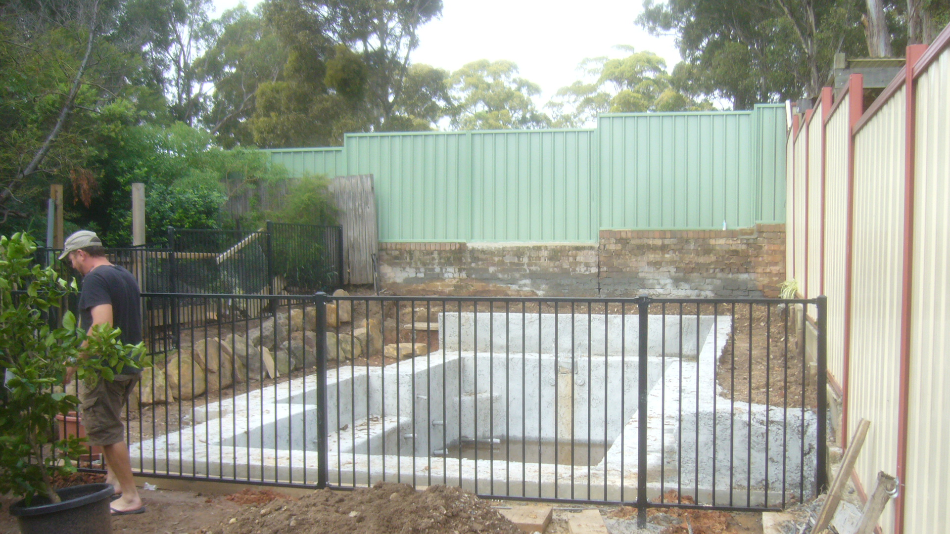 Black flat top pool fence around a pool under construction